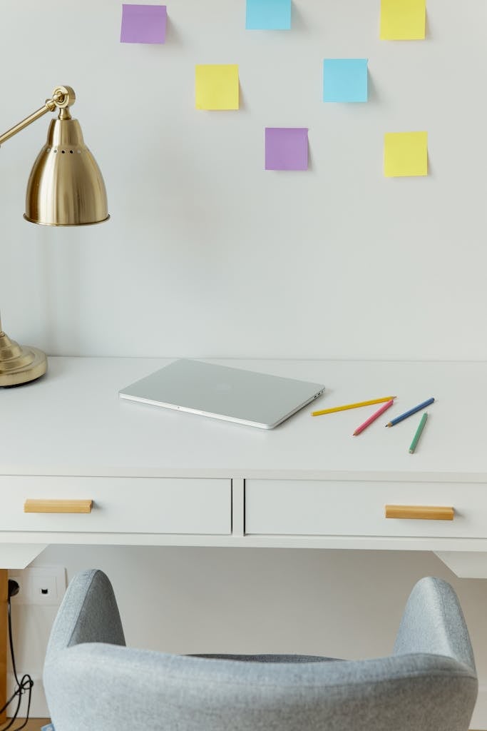Minimalist workspace featuring laptop, sticky notes, and colorful pens on a white desk.